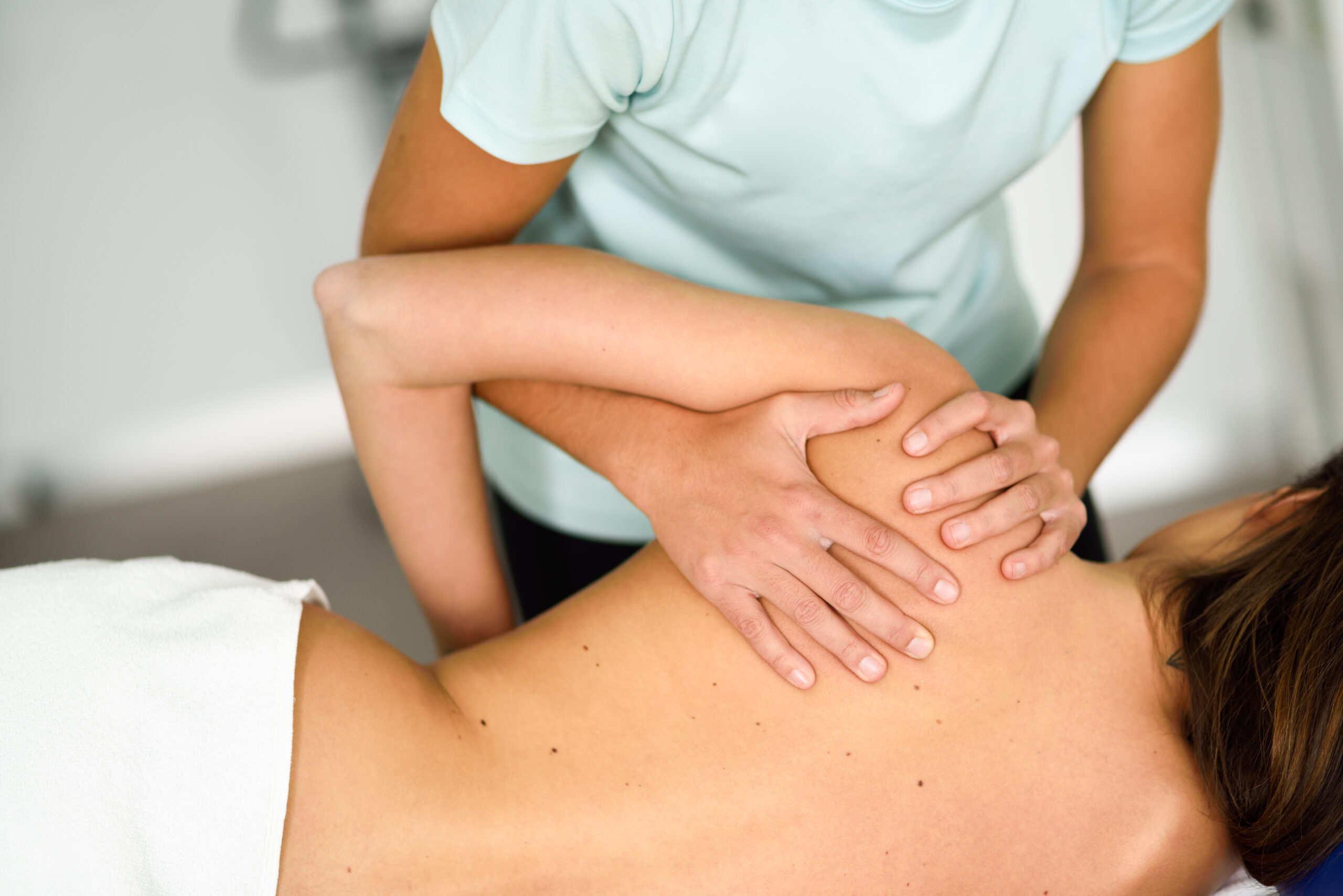 Professional female physiotherapist giving shoulder massage to a